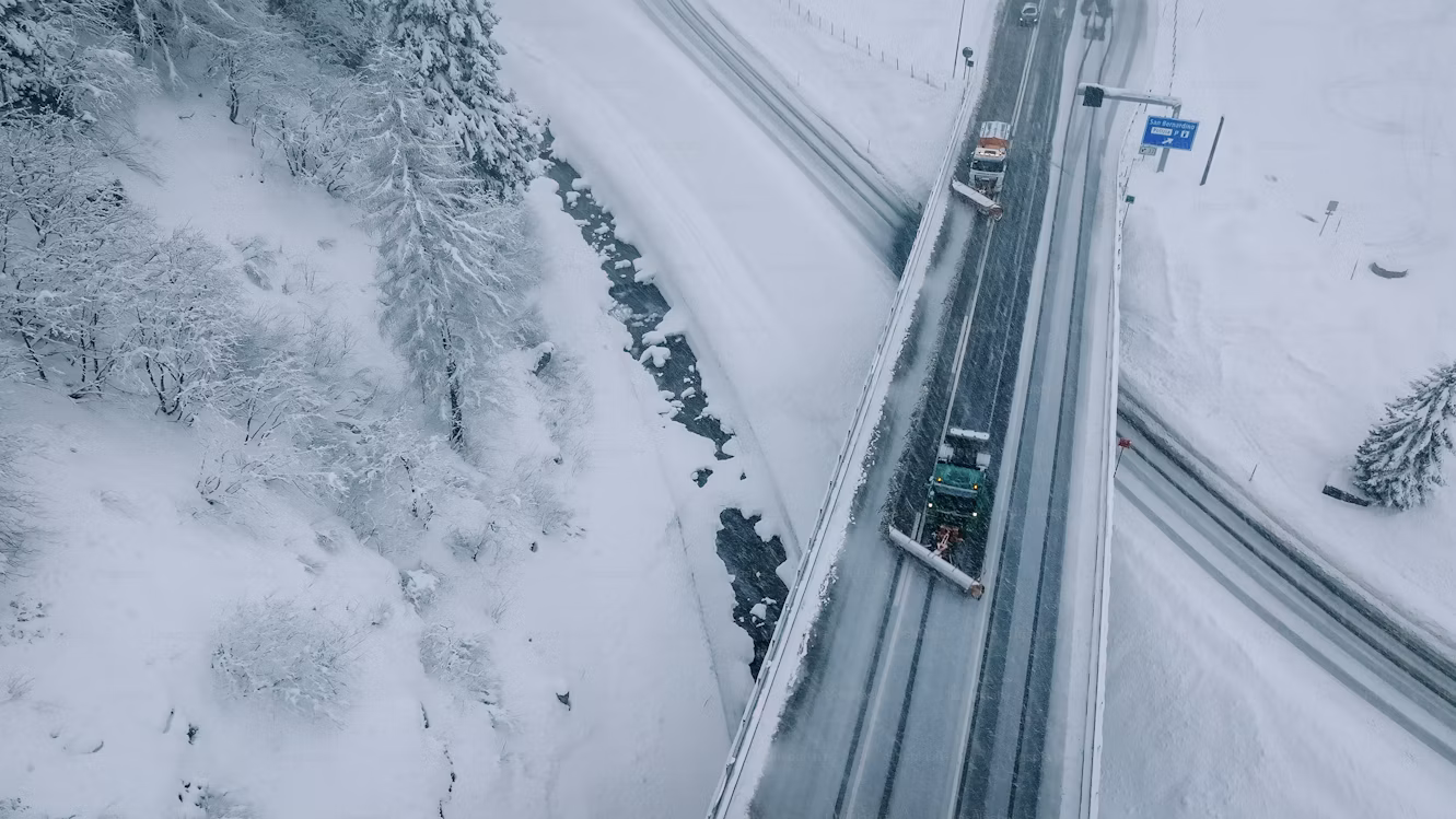 Fleet of snow plow trucks on a snowy road